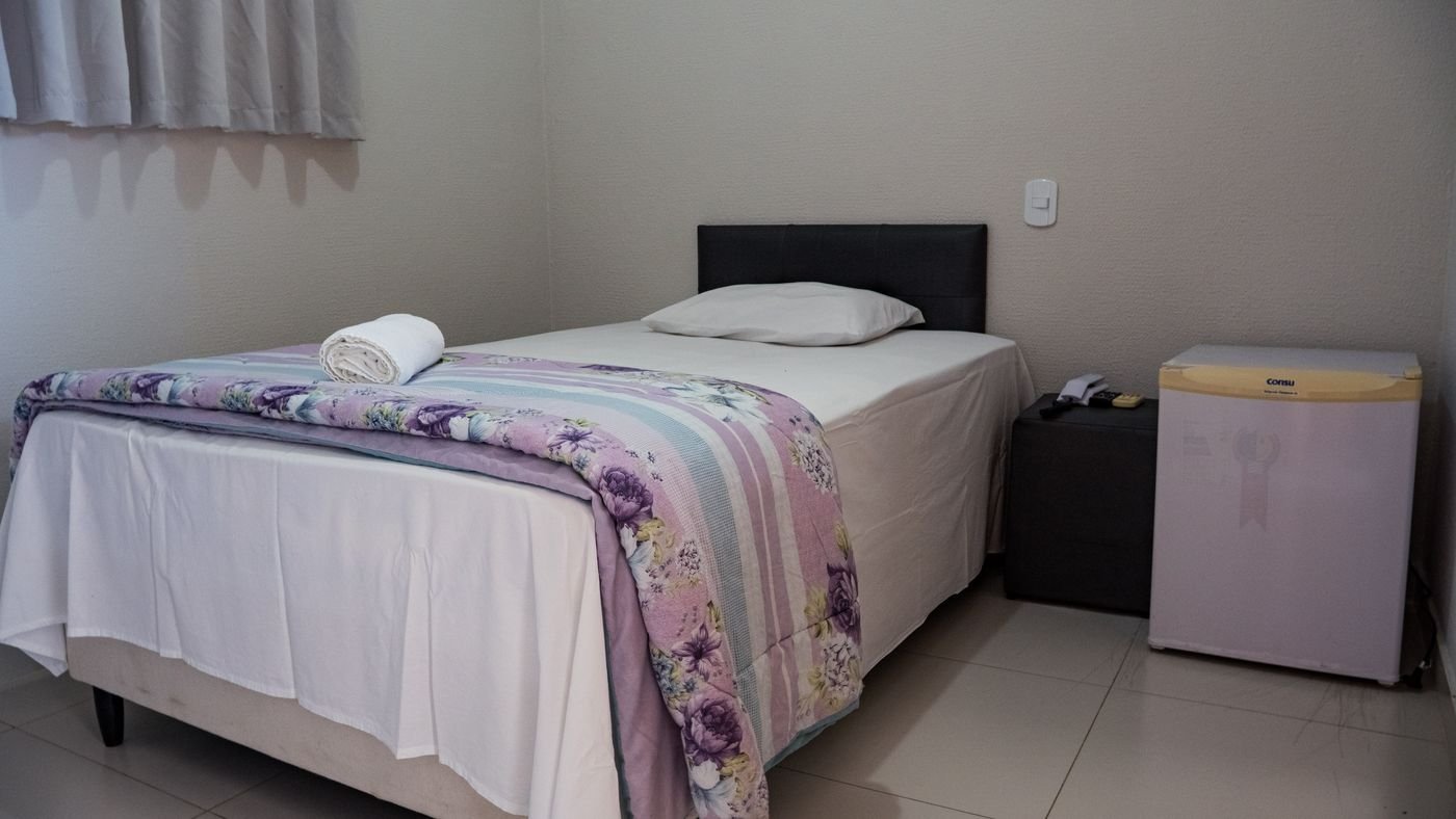 Cama de solteiro arrumada no apartamento individual do Hotel Katraca Palace